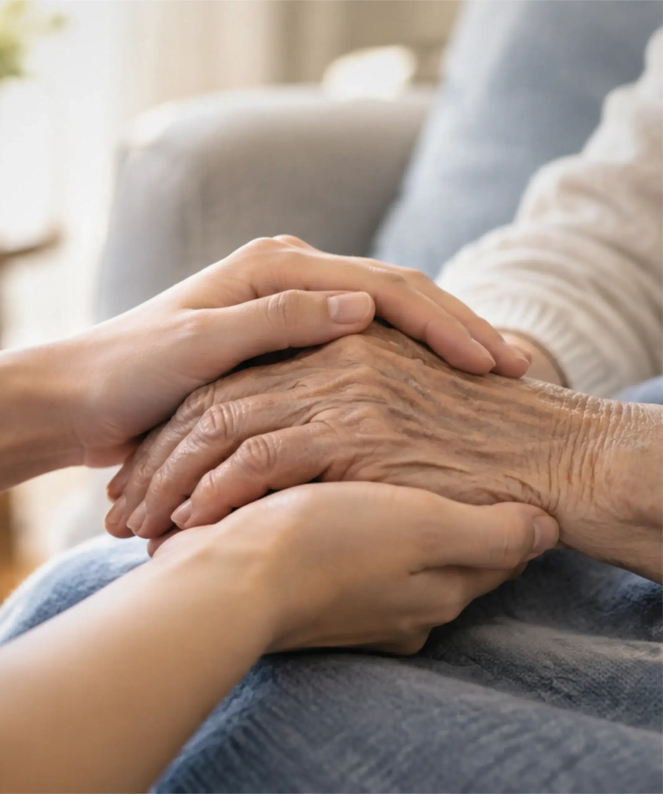 Caregiver holding an elderly person’s hands with compassion, providing elderly care in Singapore