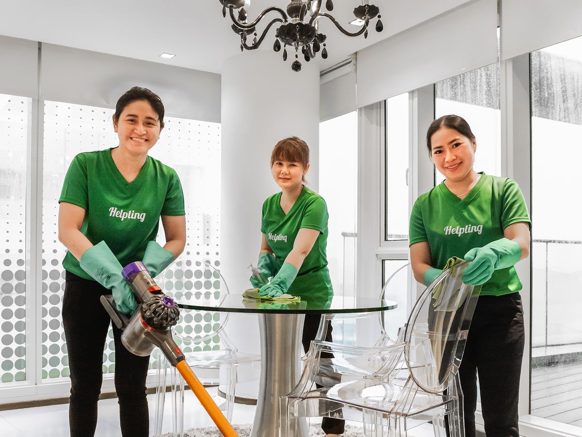 Three early Helpling housekeepers in green Helpling t-shirts cleaning a bright dining room