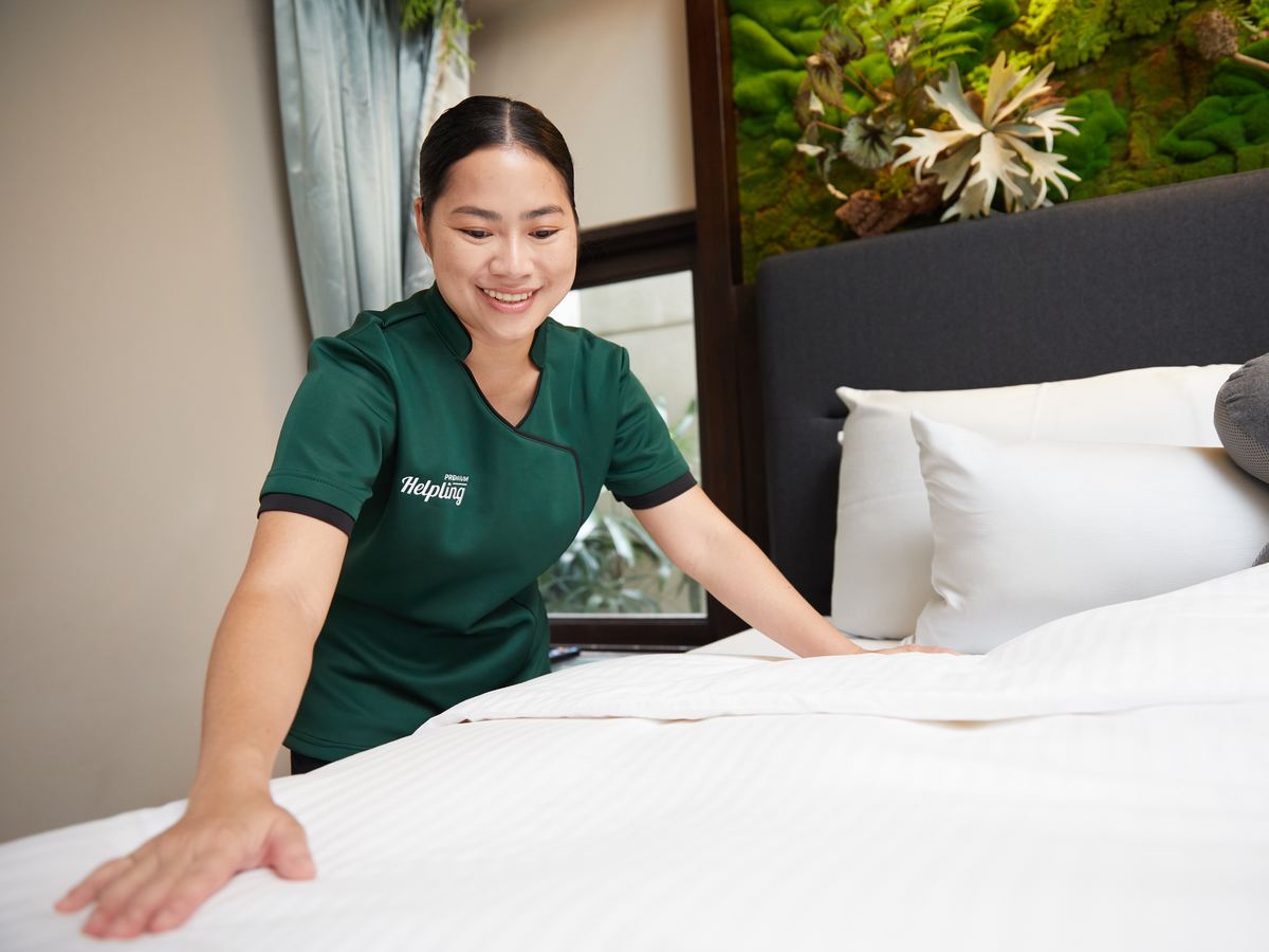 Helpling professional smoothing crisp white bed linen to a hotel-grade finish