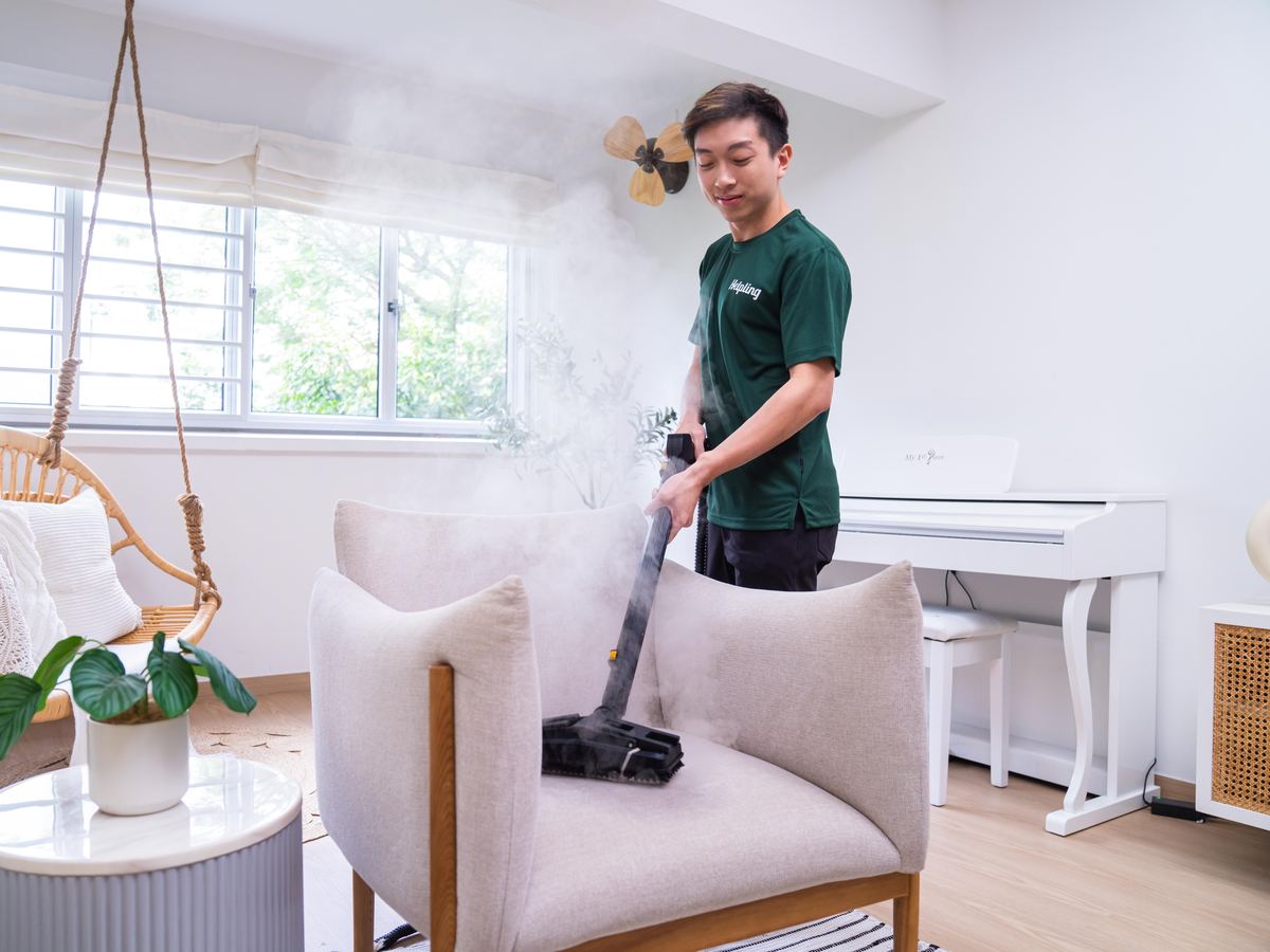 Helpling professional steam-cleaning an armchair in a bright living room